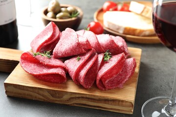 Slices of delicious sausage with thyme served on grey table, closeup