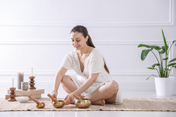 Woman with singing bowls on floor indoors