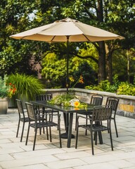 Obraz premium Outdoor patio with black furniture and a large beige umbrella surrounded by lush greenery.