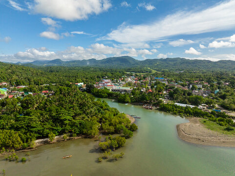 Tropical Island with houses and river. Looc, Poblacion. Blue sky and clouds. Tablas Island. Romblon, Philippines.