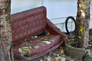 Closeup of Old brown sofa left in the forest covered with grass with natural background at Thailand. selective focus.