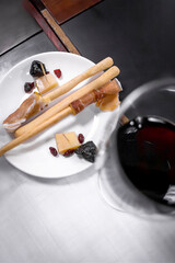 Food Pairing. Glass of red wine paired with grissini, cheese, and dried fruits