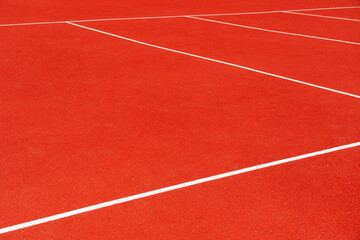 Bright red track surface with white lines creates a vibrant setting for athletic activities. Ideal for running events and training sessions, energized by sunlight