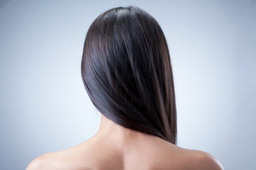 Fototapeta premium Woman With Long Silky Brown Hair Poses From The Back In Studio