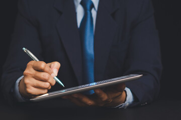 Close-up of businessman using stylus on digital tablet for signing or writing.