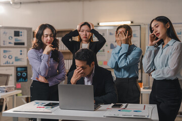 Obraz premium Asian businesspeople experiencing stress and frustration while working on a project together in the office, demonstrating the pressures of the modern workplace