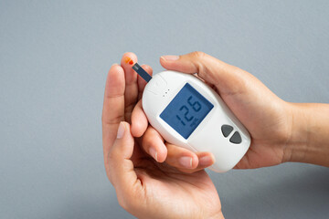 Fototapeta premium Woman's hands checking diabetes and hyperglycemia with digital blood sugar meter. Healthcare and medical concept 