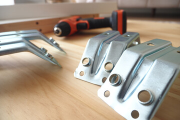 Hardware tools and metal brackets arranged on a wooden surface