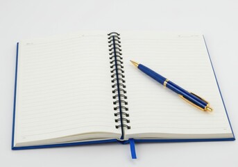 Open spiral notebook with blank pages and a blue pen resting on the right side of the notebook page