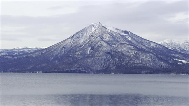 Snow-Capped Mount Yotei Rising Above the Calm Waters of Lake Toya Under a Cloudy Sky