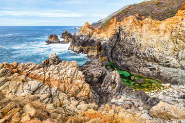 Stunning coastal landscape along California's Highway 1, featuring rugged rocky formations, and the vast blue ocean. A breathtaking natural scene showcasing the raw beauty of the Pacific coastline