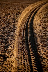 tire tracks in the sand of a field at sunset