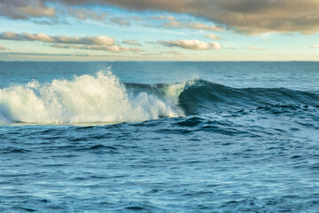 Powerful ocean waves with turquoise and blue hues crash and foam, creating a dynamic and energetic seascape. The raw beauty of nature, the motion of water, and the force of the ocean captured in