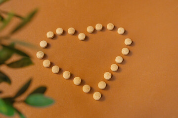 Photograph of natural pills forming a heart with green leaves on the left side
