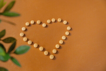 Organic medicinal pills placed in a heart shape on a brown surface
