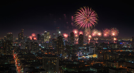 City Lights Celebrated: Fireworks light up a stunning cityscape at night, with illuminated buildings creating a beautiful backdrop. Perfect for evoking a sense of festivity and celebration.