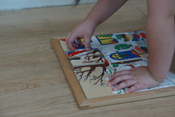 Child playing with wooden puzzle on the floor