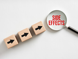 Magnifying glass showing side effects and wooden cubes with arrows pointing towards it