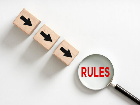Magnifying glass showing rules word with three wooden cubes with arrows pointing towards it