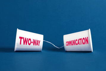 Two-way communication concept represented by plastic cups and string on blue background