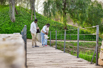 Fototapeta premium Family walking on wooden bridge in park, enjoying nature together