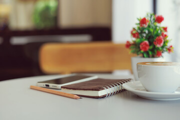 Close-up shot, latte coffee and notebook with mobile phone on table in cafe, relax in the morning in cafe before work