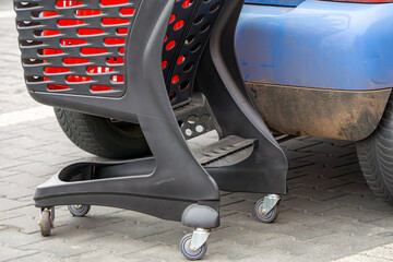 a shopping cart that hit the rear bumper of a blue passenger car. The cart is wedged and very close to the vehicle. The car shows signs of impact damage.supermarket car park © Adam