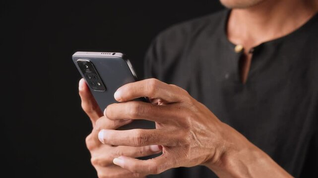 a man wearing black shirt is scrolling his smartphone to search for information on the internet