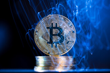 Glowing blue energy is flowing through and around a large, physical bitcoin cryptocurrency coin resting on a stack of coins, representing the dynamic and volatile nature of digital currencies