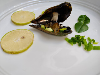 close up of a plate of sea scallops with sliced ​​lemon and vegetables