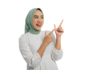 Excited young Asian woman in green hijab and white blouse pointing finger at copy space for text advertisement isolated on transparent background