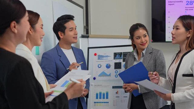 Collaborative asian business professionals analyzing financial reports and discussing growth strategies in corporate meeting setting