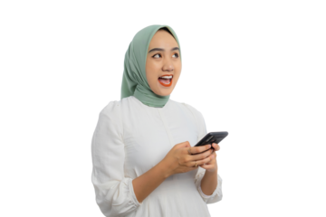Surprised young Asian woman in green hijab and white blouse using smartphone and looking aside at copy space isolated on transparent background