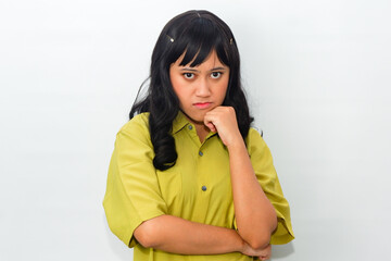 An enthusiastic Asian woman wearing a green shirt with an angry expression, crossing her arms