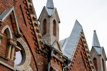 Architectural styles of the Catholic Church, view from below. Fragment of the decoration of the church in the neo-Gothic style. Roman Catholic church made of brick in the neo-Gothic style