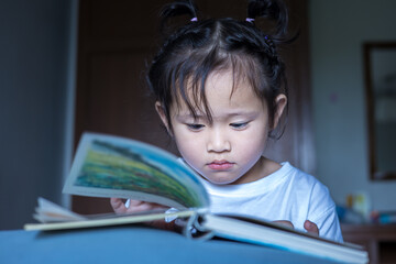 A little girl reading a bedtime story in bed.