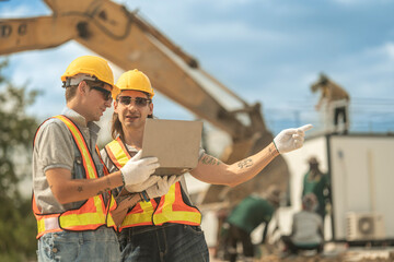 Engineering team on-site wearing protective equipment, analyzing project data with heavy machinery...