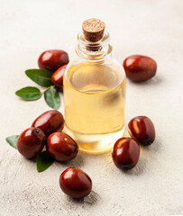 Jojoba oil in bottle with ripe jojoba fruits.