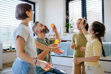 Portrait of father with three daughters blowing bubbles.