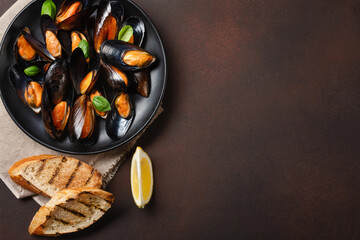 Seafood mussels and basil leaves in a black plate with bread slices, burlap on rusty background