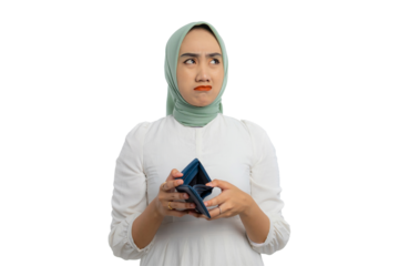 Sad young Asian woman in green hijab and white blouse holding empty wallet and looking aside at copy space isolated on transparent background