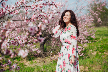 woman walking in flower dress in spring blooming garden