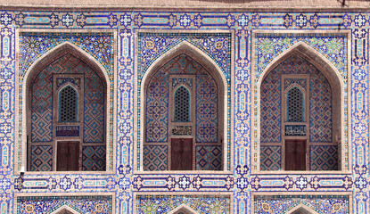Obraz premium Famous landmark - Ulugh Beg Madrasah on Registan square, Samarkand, Uzbekistan. Arches with tile ornament in the courtyard of Ulugh Beg Madrasa. Text on the wall is a quote from the Quran