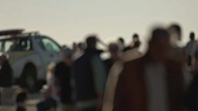 Blurred crowd gathering near emergency vehicle with flashing lights