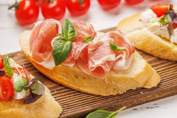 Tasty antipasto toasts featuring classic caprese with mozzarella and tomatoes, and savory prosciutto with herbs