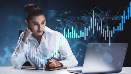 Businesswoman analyzing financial data charts on laptop with futuristic digital interface and glowing light over dark abstract background concept.