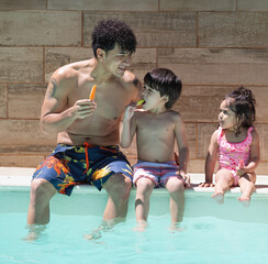 Single father and children eating popsicles, relaxing by swimming pool on summer day.