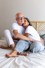 Obraz premium Happy mature couple embracing, relaxing together on bed. Eyes closed. Feeling connection and love. Vertical.