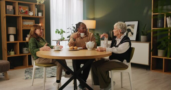 Tea, support and senior women in a house with care, trust and conversation, relax and bonding together. Talking, retirement and group of elderly friends at home with drinks, chat or gossip at reunion