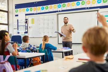 Teacher asking his students a question at elementary school